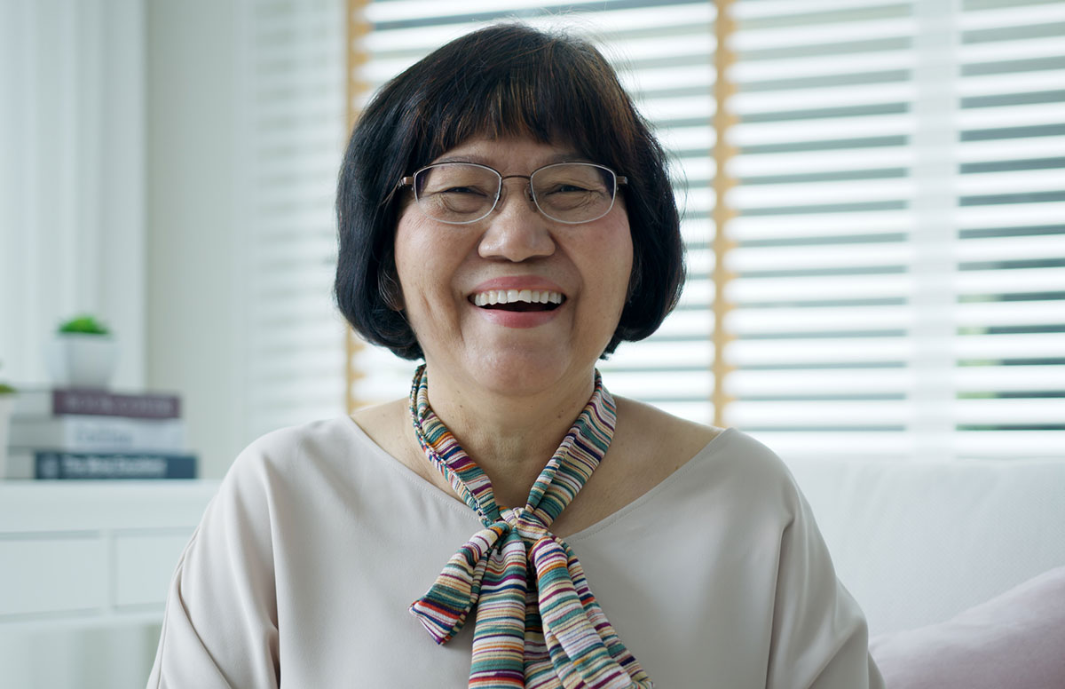Portrait style photo of Asian older woman wearing glasses and smiling large!